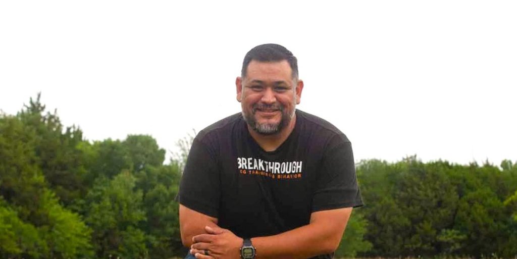 Dog trainer Eli Vega kneeling over a dog
